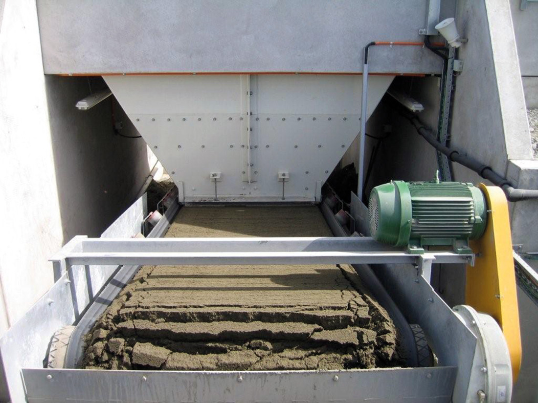 Upclose photo of a truck unloader processing sand | featured image for Truck / Railwagon Unloader.