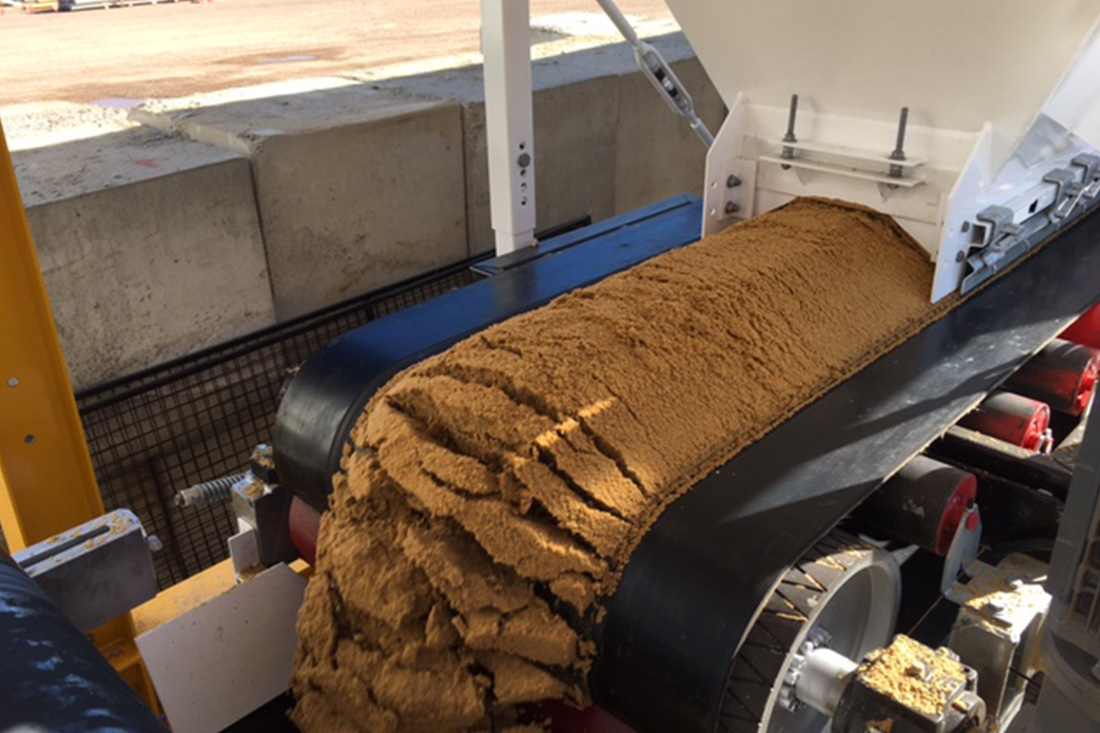 Photo of a belt weigher processing sand | Featured image for the Aggregate Weigh Trailer Page for CMQ Engineering.
