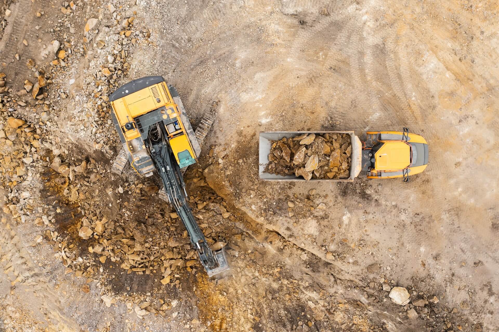 Backhoe loading stone in a truck | Featured image for the What is the Difference Between Quarrying and Mining blog from CMQ Engineering Australia.