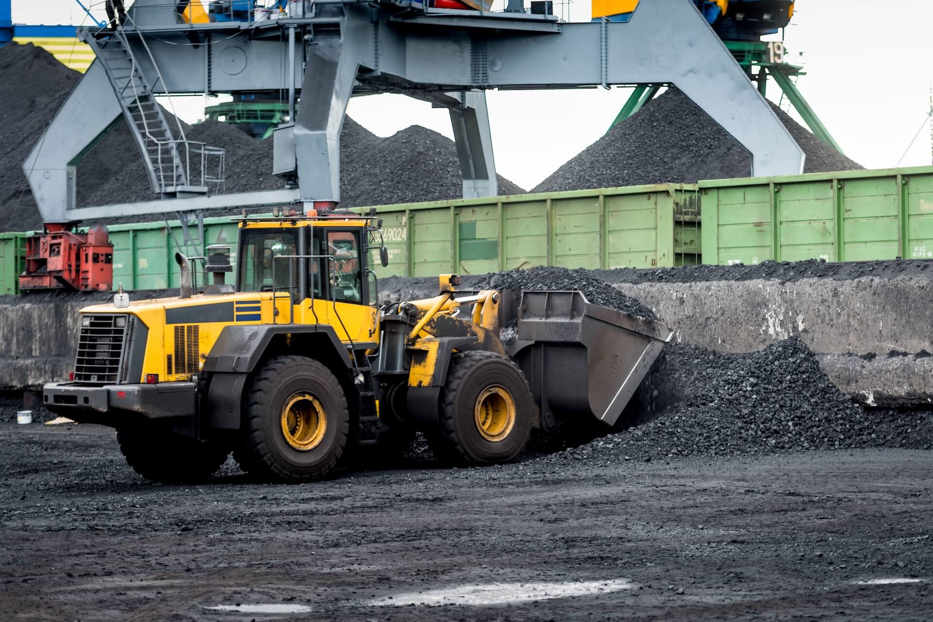 Yellow earth mover scooping up rock | Featured image for the Types of Mining Equipment - Exploring the Industry’s Iconic Machinery blog from CMQ Engineering Australia.