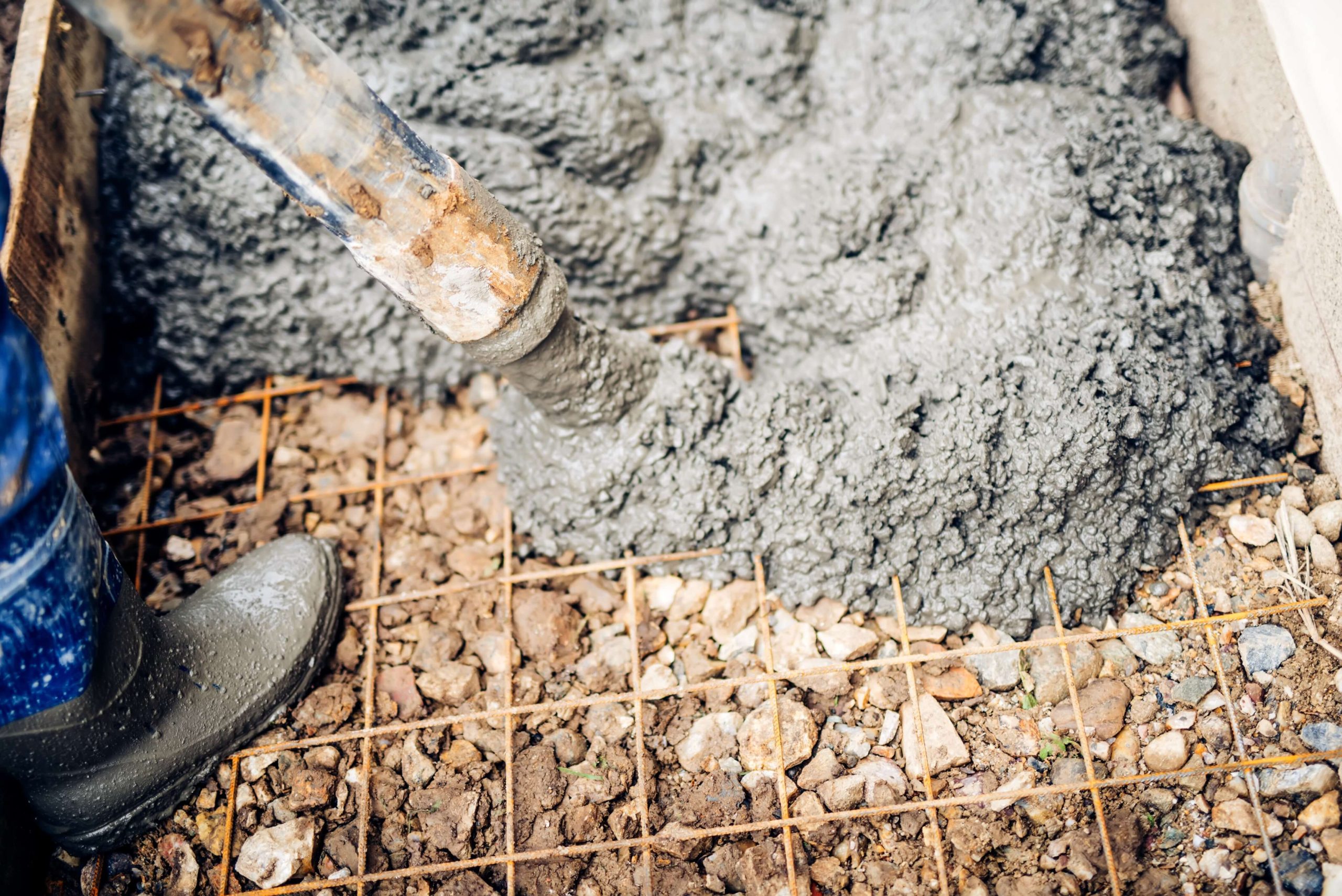 Close up of construction workers using cement pump tube | Featured image for the What is Concrete Reclamation blog from CMQ Engineering Australia.